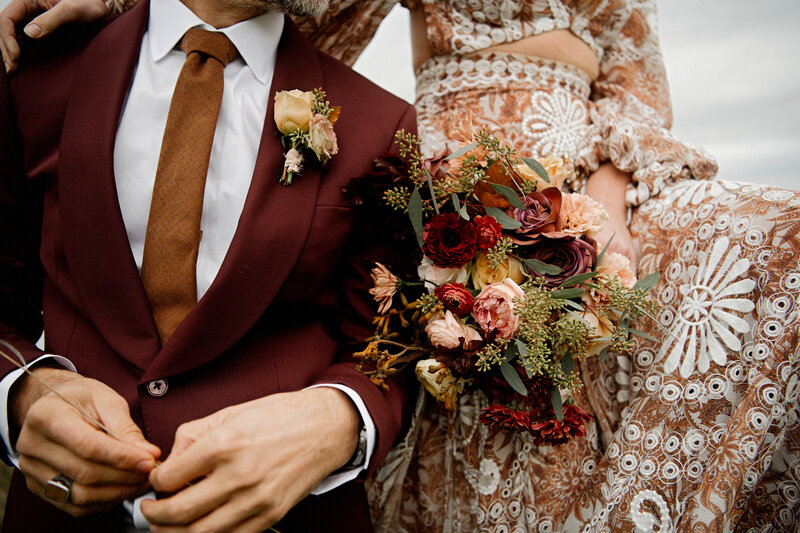 Detail of a bride and groom in autumn shades of rust mustard burgundy and brown