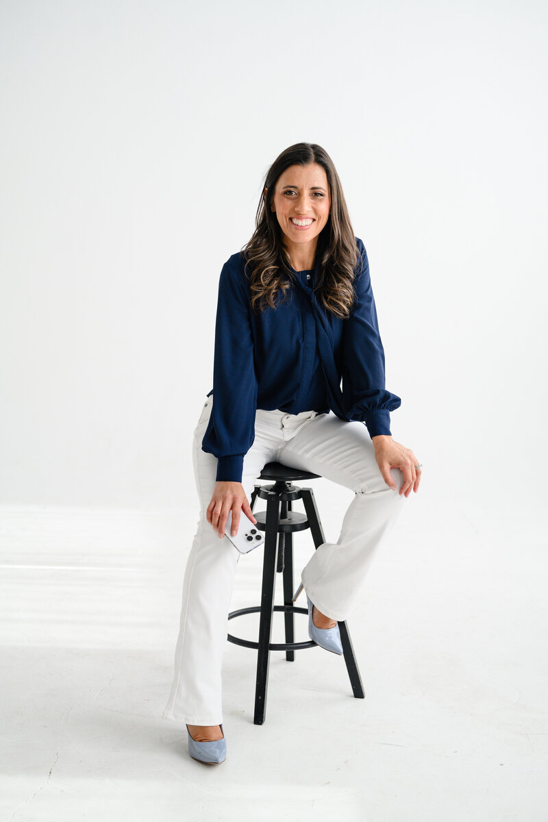 Jo, founder of Branding by Jo, smiles with a camera in her Orlando studio, highlighting her enthusiasm and expertise in brand photography.