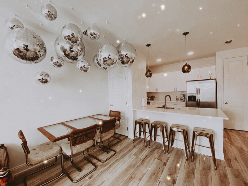living and dining room with white walls and disco balls hanging from the ceiling