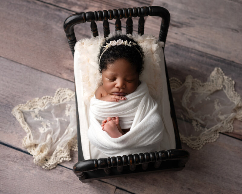 Austin newborn photographer capturing swaddled baby in rustic wooden crib during studio session