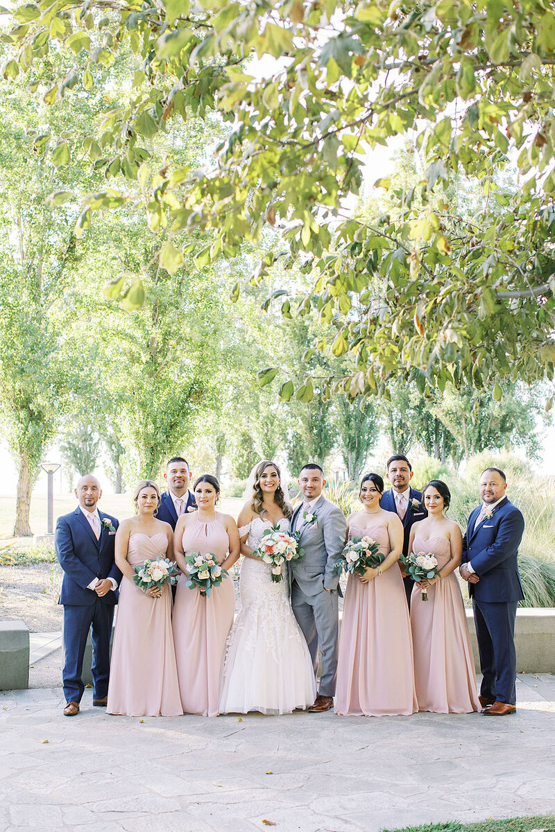 11-radiant-love-events-wedding-party-outdoors-green-trees-overhead-dusty-pink-bridesmaid-dresses-navy-grooms-suites-romantic-elegant-timeless