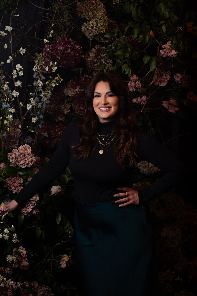 Amanda Lamar - A Morgan Floral Design Owner, image of a woman with a Dutch Masters Inspired floral vignette dark background and antique style florals