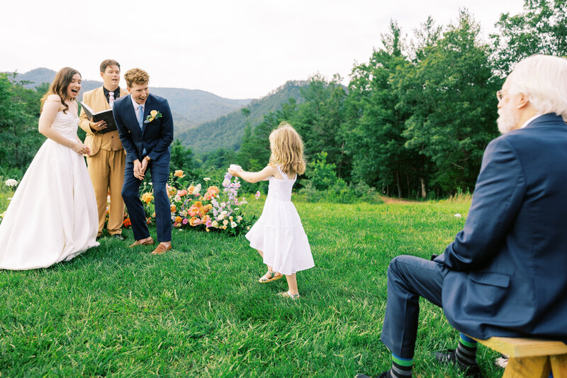 The bride and groom are ecstatic as the ring bearer brings them the rings amongst the beautiful backdrop of the North Carolina hills at wedding venue Paint Rock Farm, by film photographer Megan Lynn of My Sun and Stars Co.