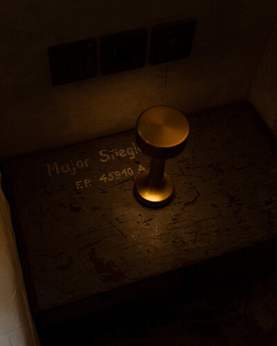 Close-up of a brass bedside lamp on a rustic wooden table at a boutique hotel in Bali.