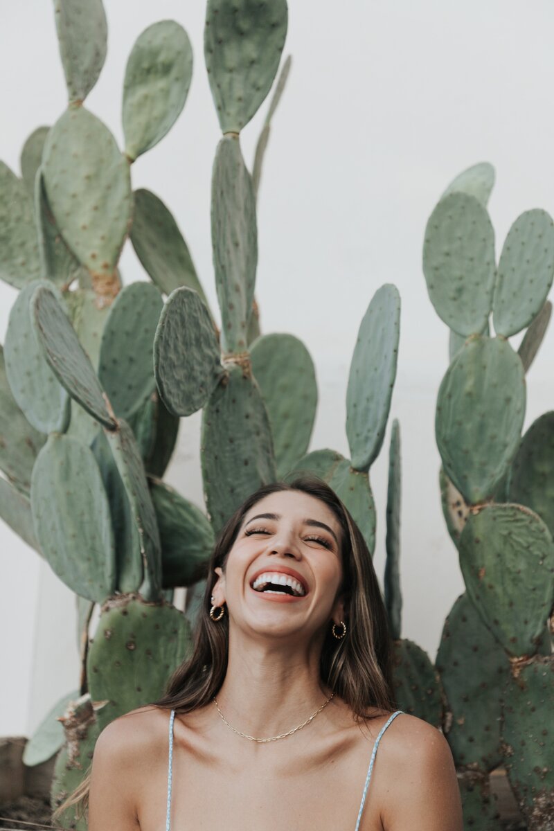 Happy smiling woman standing in-between flat-faced cacti