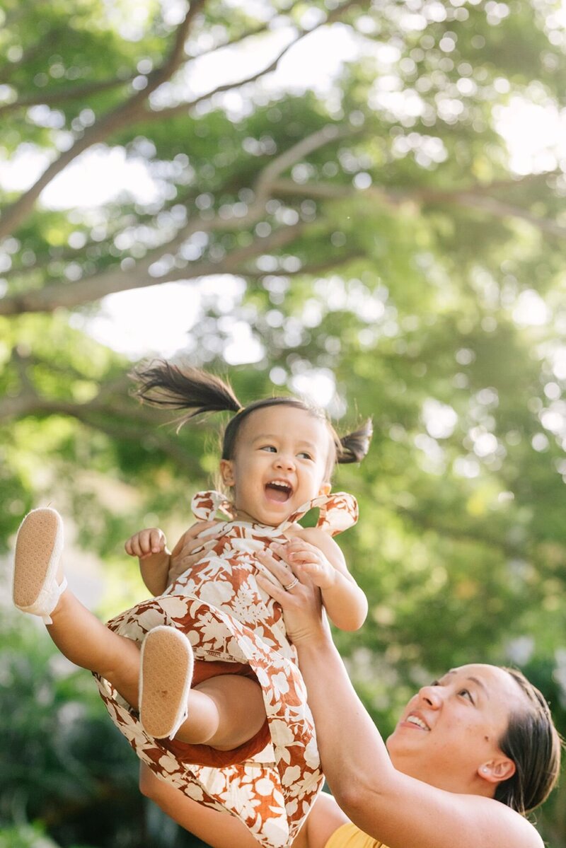A mother throws her baby up in the air, smiling.