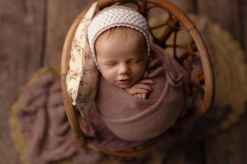 Timeless textures and sweet florals bring warmth to this newborn girl’s portrait in a vintage chair.