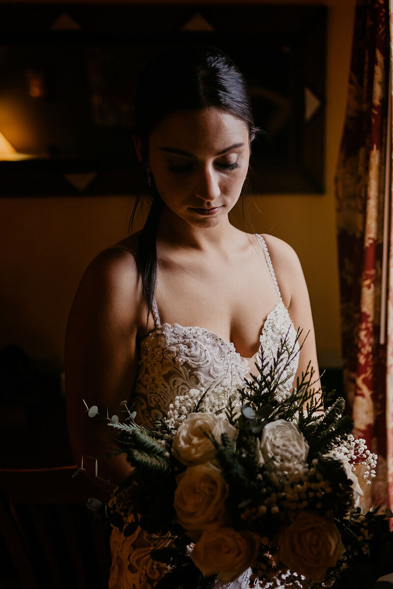 Bride quietly reflecting on her thoughts as she looks down at bouquet before wedding ceremony by nh wedding photographer Lisa Smith Photography
