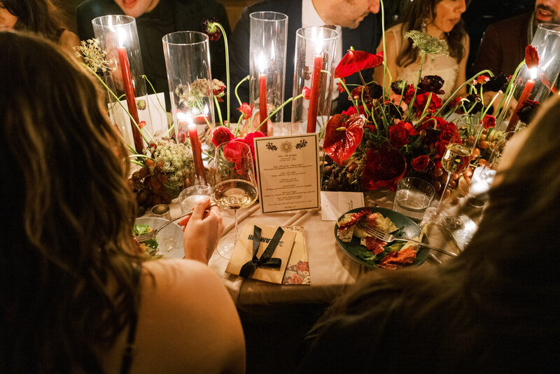 A candlelit birthday celebration in Tribeca with a luxurious tablescape adorned with red floral arrangements, glowing candles, and elegantly set dinnerware, creating an intimate and festive atmosphere.