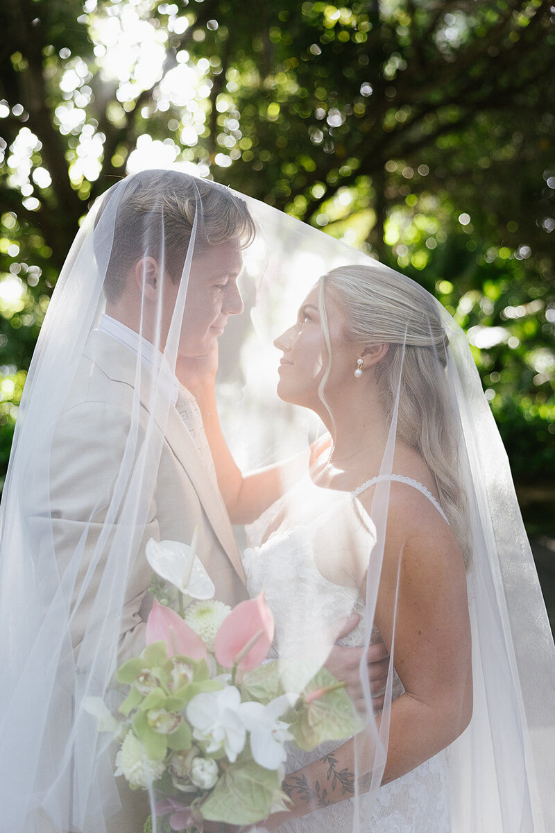 Bride and groom under brides veil white they look at each other