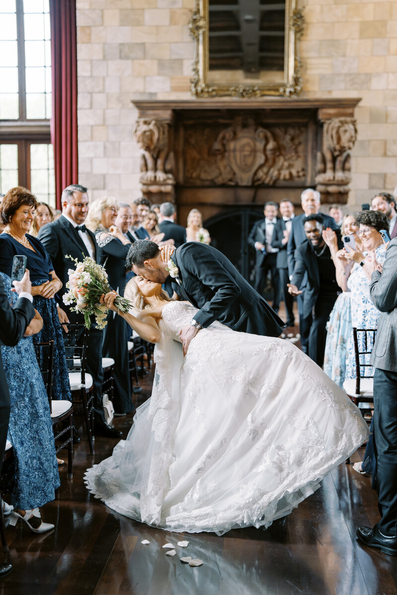 Indoor ceremony photo of groom kissing bride in the aisle at Dover Hall wedding venue
