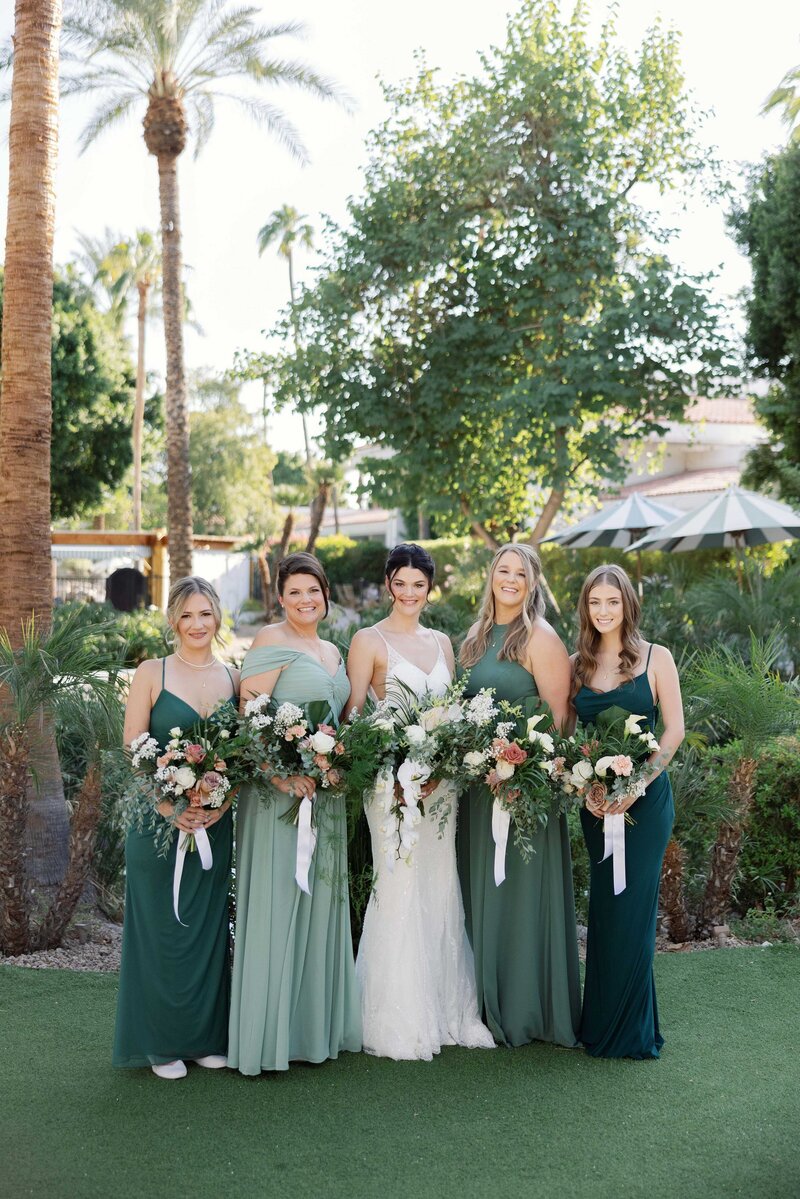 bride and bridesmaids smile towards the camera while holding tropical bouquets