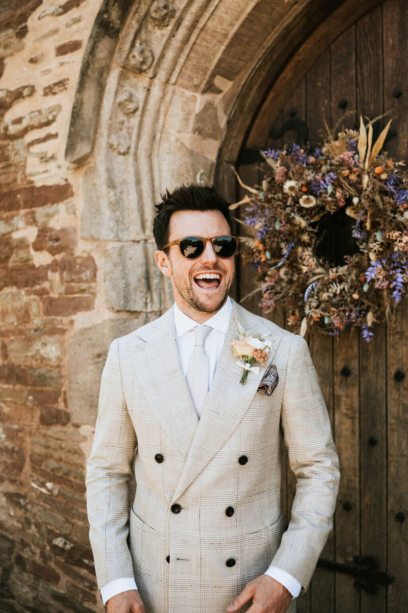 Groom wearing a beige suit with a buttonhole at Broadfield Court