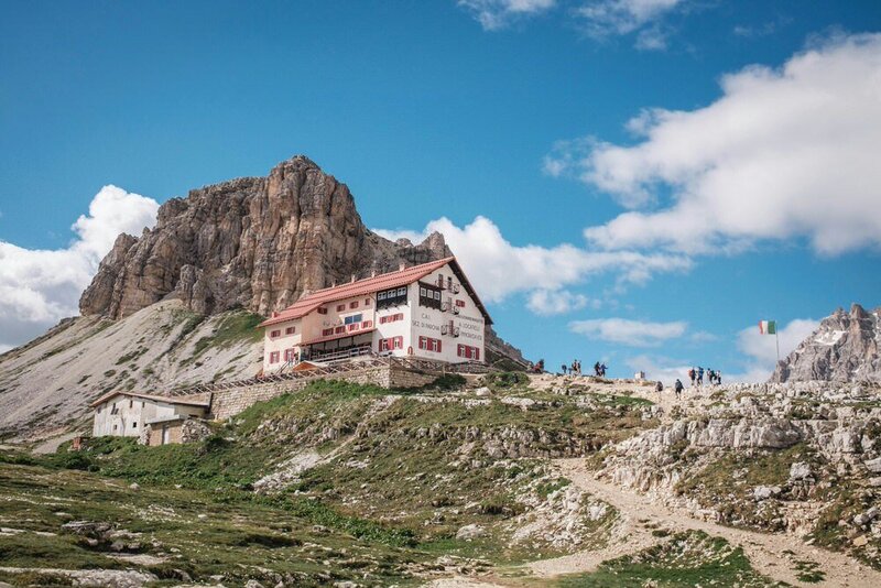 three story Rifugio or mountain hut with a mountain in the background