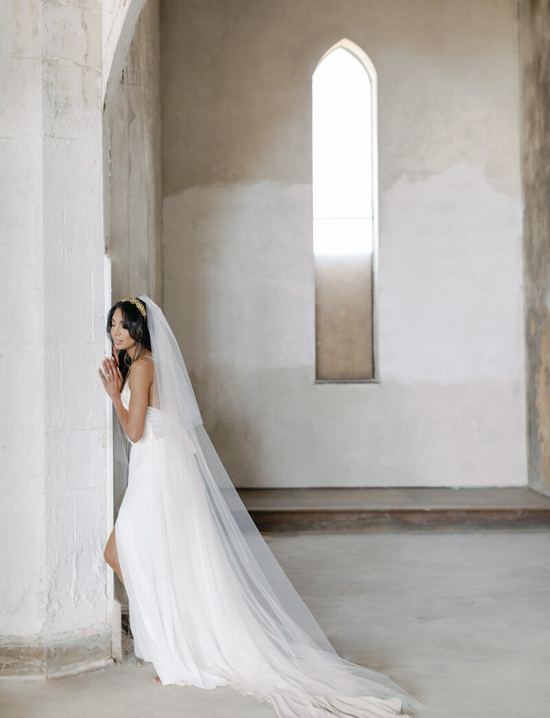 bride in long white dress and veil leans on ruins wedding venue in Italy, Croatia, Italy film wedding photographer