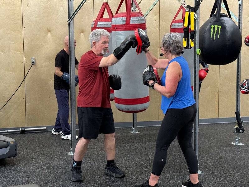Coach Lori and a warrior practice non-contact boxing in the Parkinson's Warriors Gym, representing one of the Parkinson's exercise classes activities.