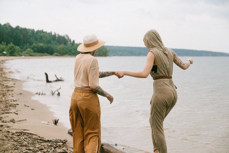 two people holding hands while standing on a beach