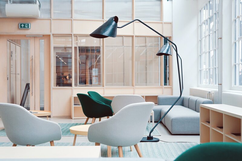 Inside a minimal office space with floor to ceiling windows and colourful arm chairs