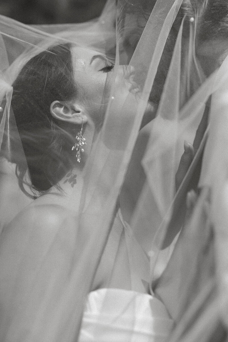 Black and white photo of a bride and groom under a veil