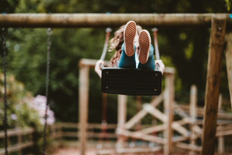 A child swinging outdoors, reflecting Wondered’s free-spirited, playful approach to education that encourages outdoor exploration and creativity.