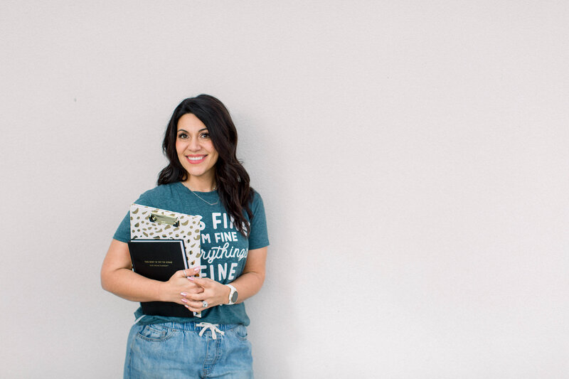 Female entrepreneur with dark hair holding books and smiling