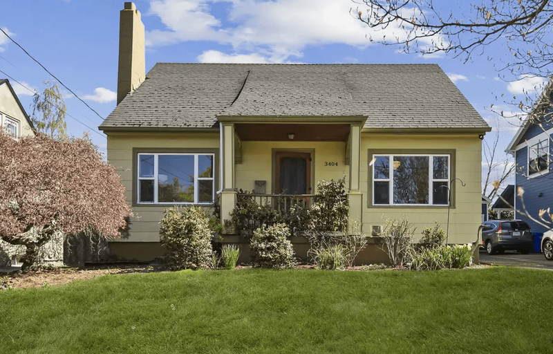 The front of a yellow house with a front porch.