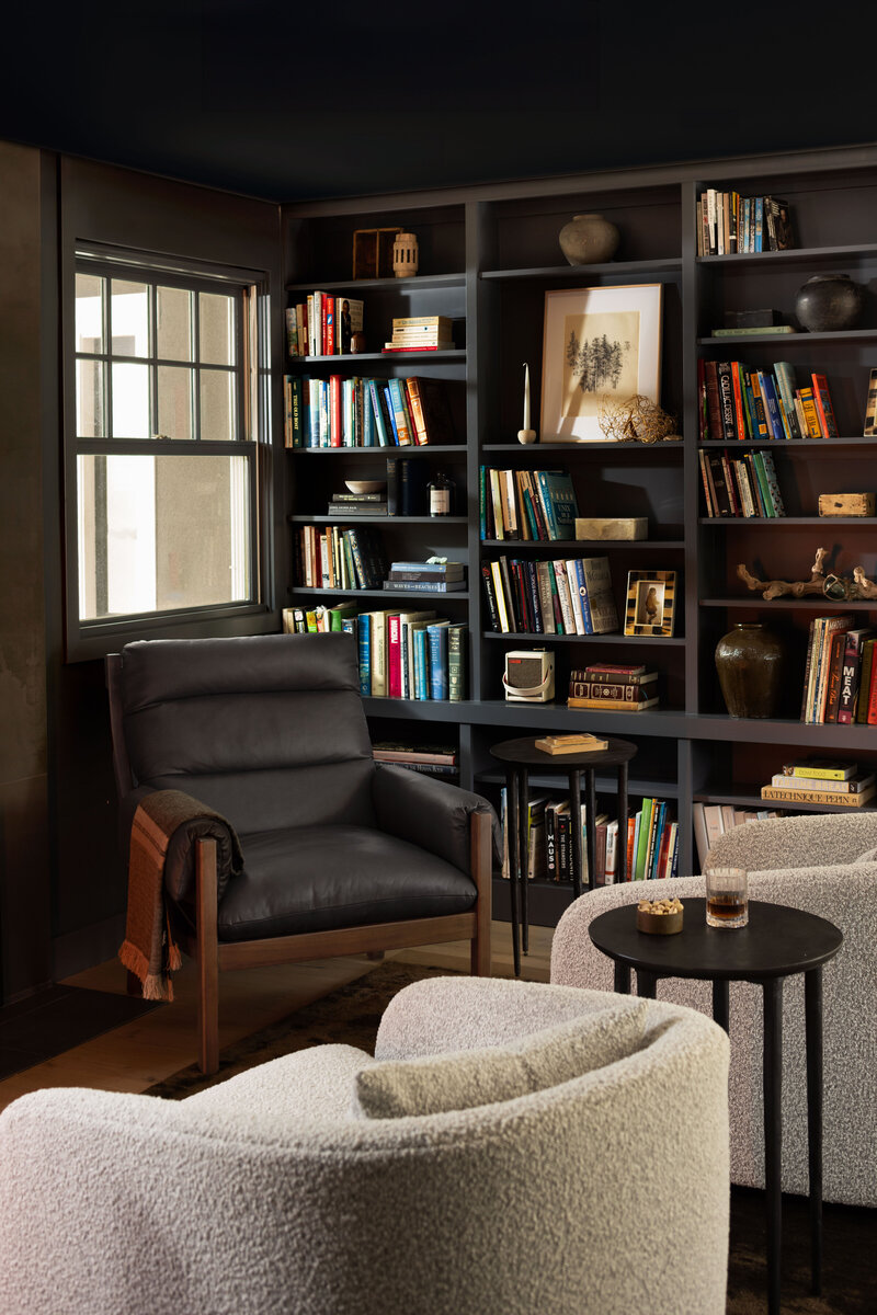 Interior design photography of a library with bookshelves, a leather chair, and natural light.