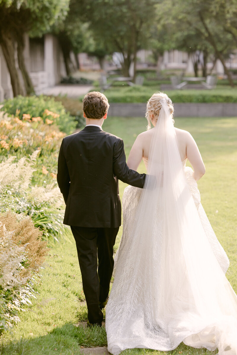 Candid photo of a bride and groom walking away in a garden