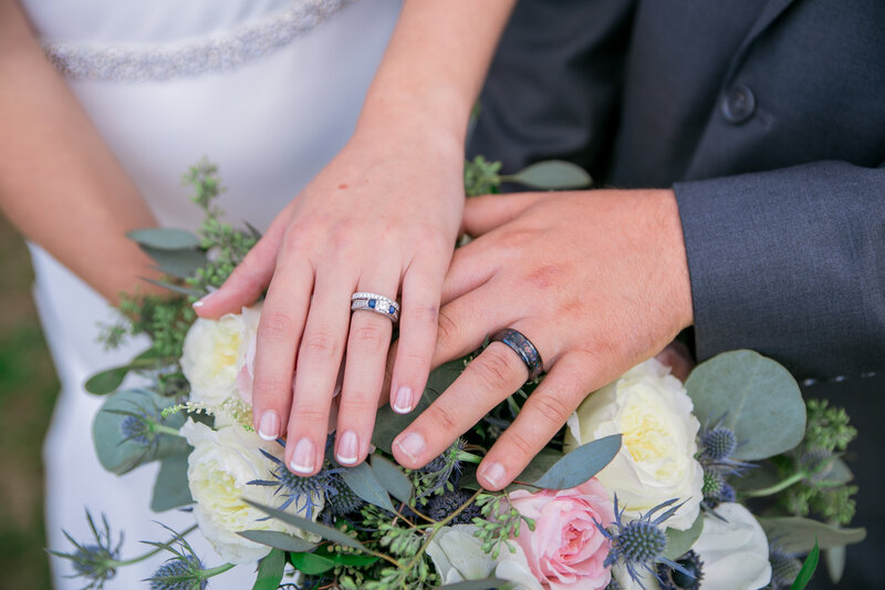 The Bride and Groom's hands with their rings above flowers | Wedding Photography