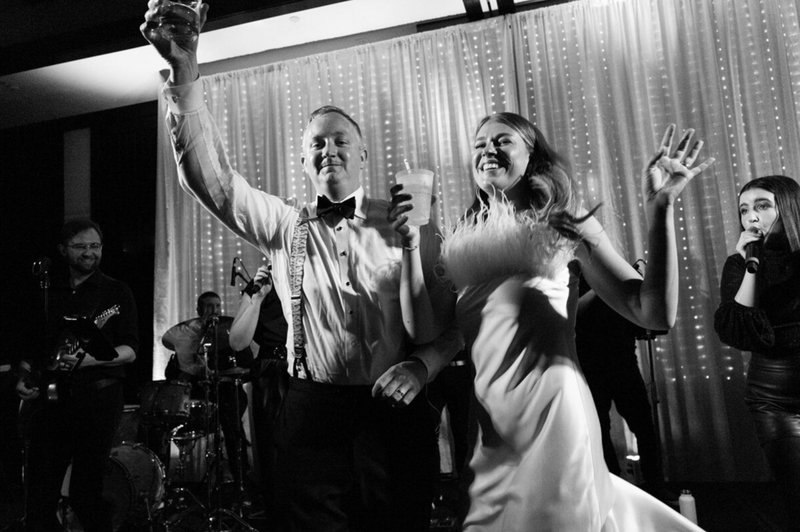 Couple dancing on stage during their wedding reception at Laguna Gloria with a live band in the background.
