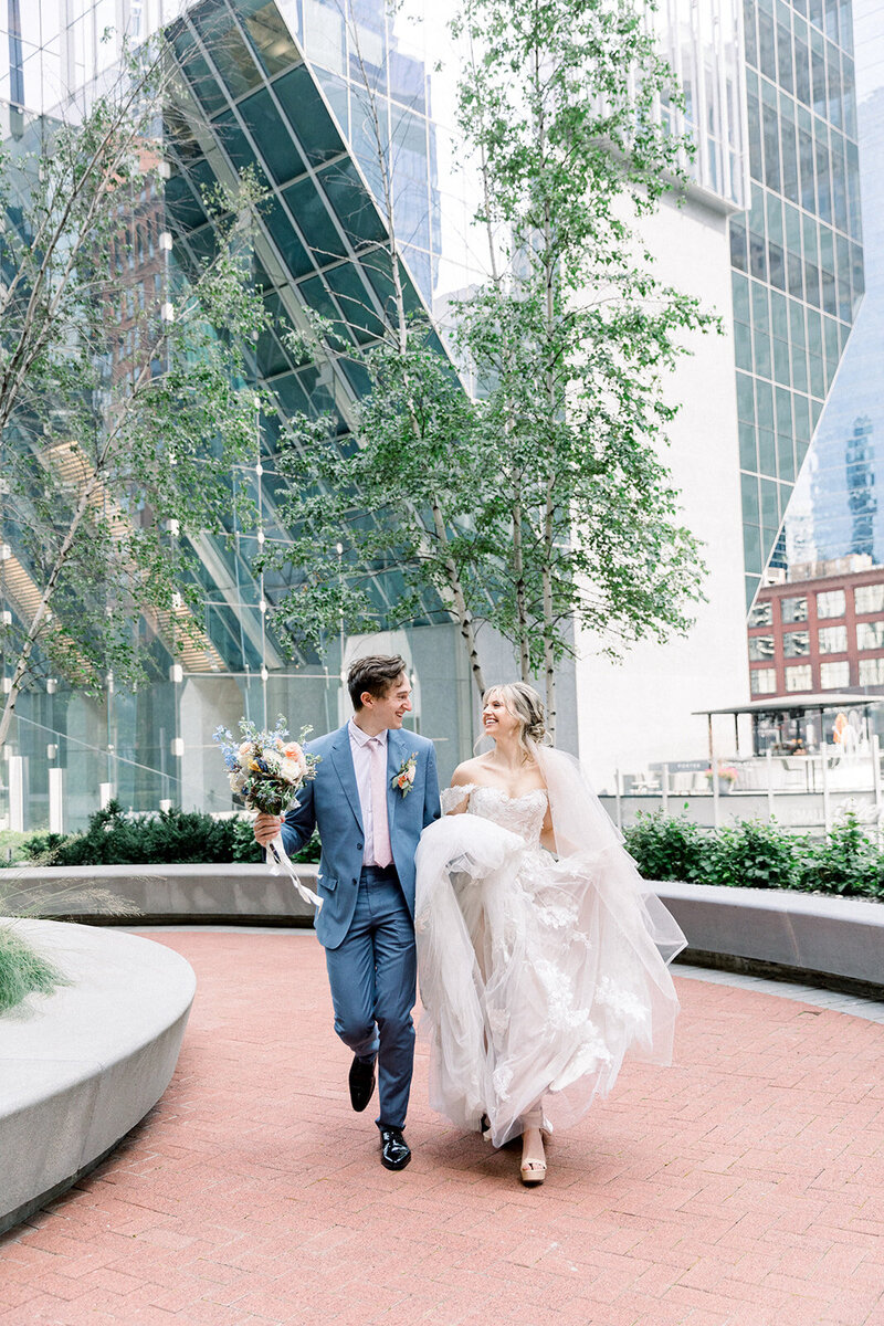 couple running in city in wedding attire