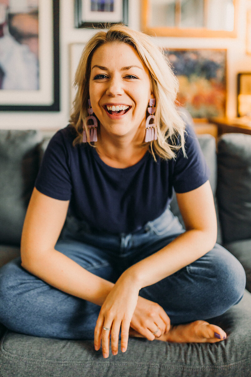 A woman wearing t-shirt and jeans is laughing.