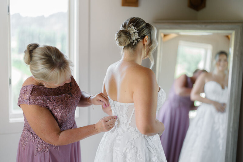 Mother carefully fixing the bride's gown