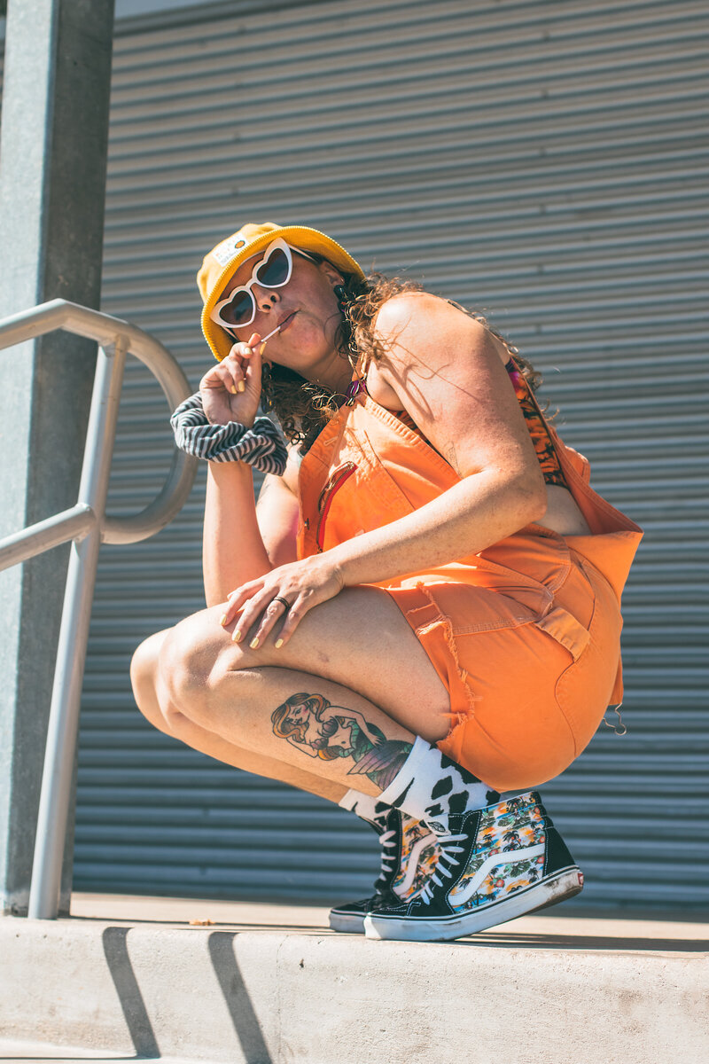 Model poses after skate session wearing Vans, overalls, stylish sunglasses and a buckethat