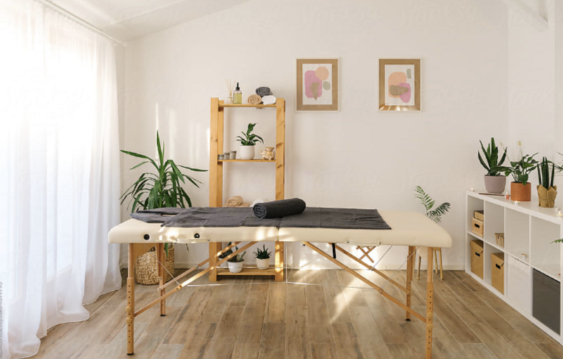 Massage table with towel and bolster in a warm, professional training room.