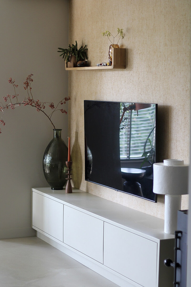 Een elegante televisiewand met een wit meubel, gecombineerd met subtiele decoratie en natuurlijke accenten