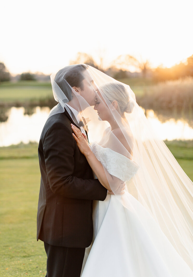 Bride and groom both under the veil smiling at historic white oak farm in Marrow Ohio