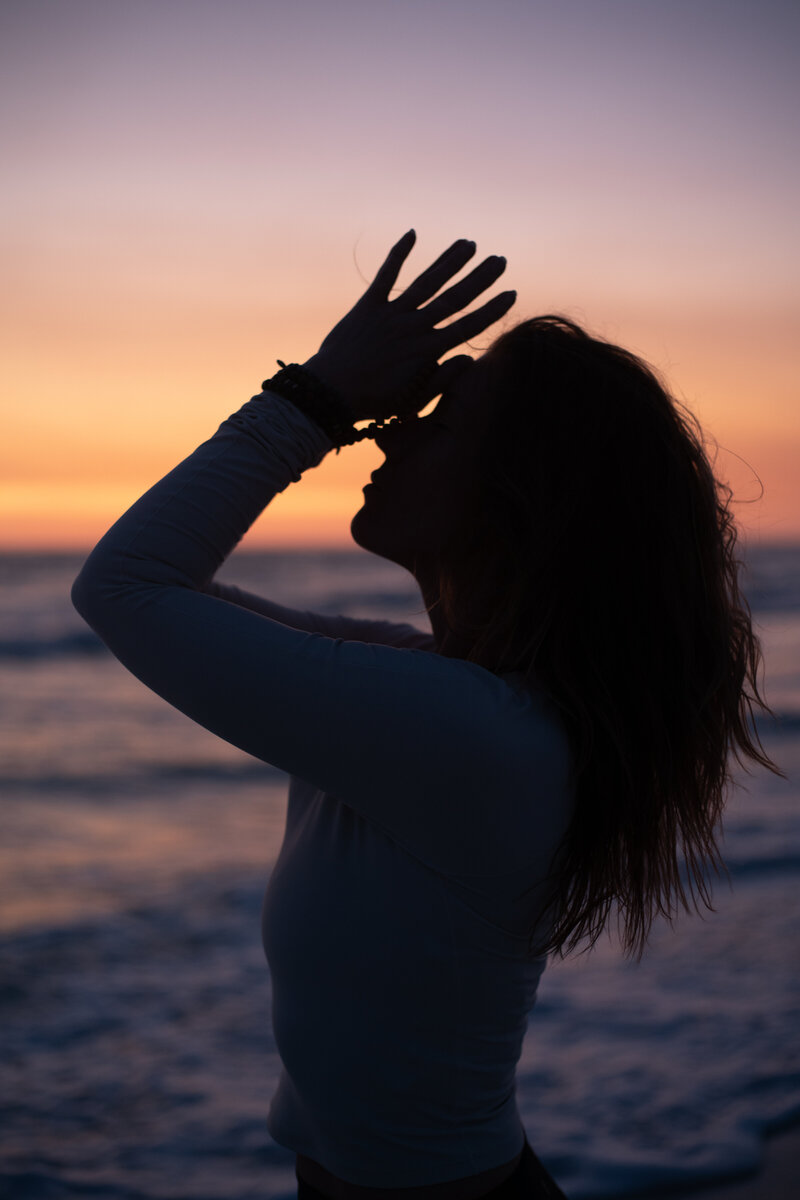 Stephanie with her hands in prayer on the beach at sunset