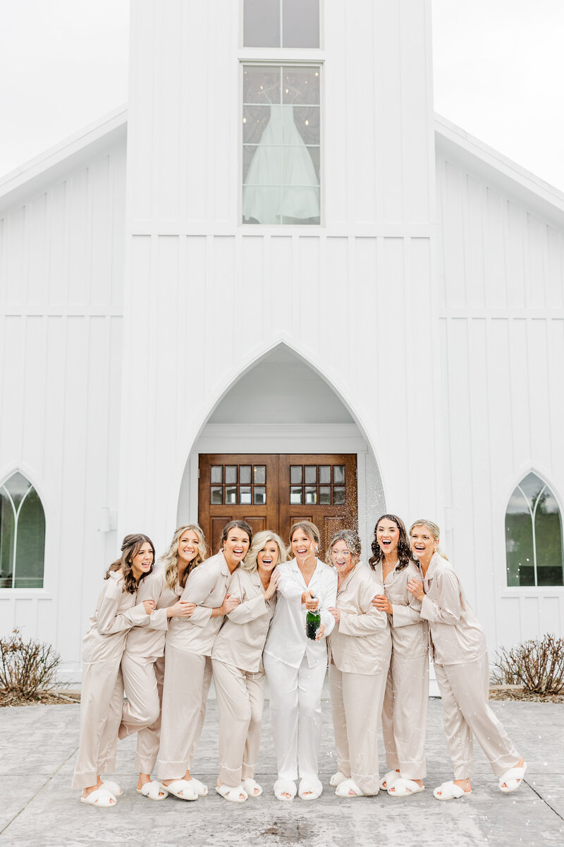a bride posing with her bridesmaids in front of a chapel