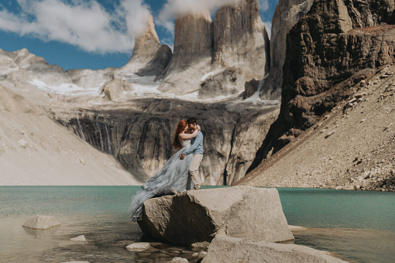 A couple. cradles each other's faces before a kiss. They are smiling with their eyes closed and the sun is shining goldem behind them.