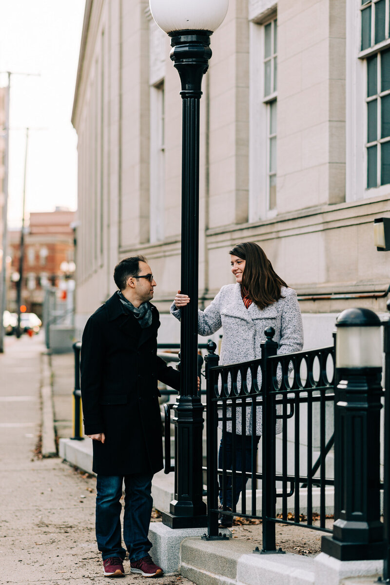 Couple looking at each other holding onto a lamp post