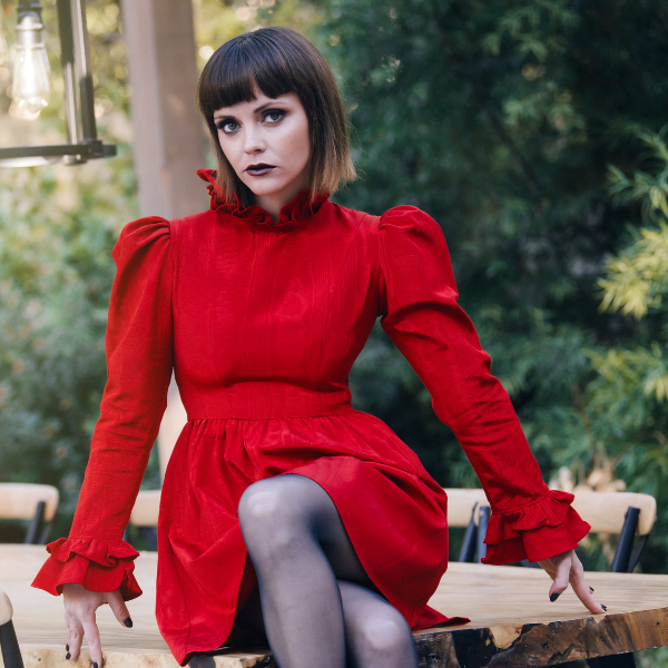actress christina ricci, a woman with brown hair wearing a red dress sitting with her hands to her side with a serious look headshots