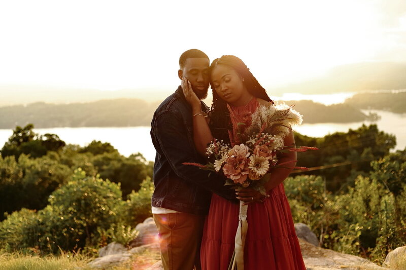 Beautiful black couple  standing on a lakeside overlook with a boho  bouquet at sunset in Alabama