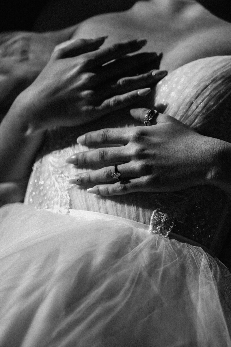 detail shot of the bodice of a brides dress and wedding ring