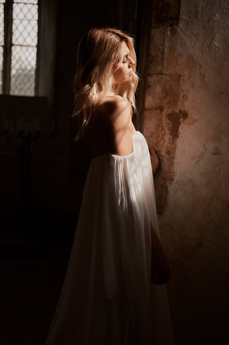 Blonde woman wearing silk wedding dress, shoulderless, handmade british bridal designer