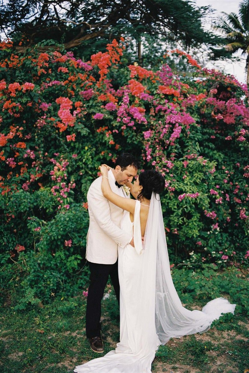 couple cuddling in front of floral wall at the intercontinental resort in Fiji
