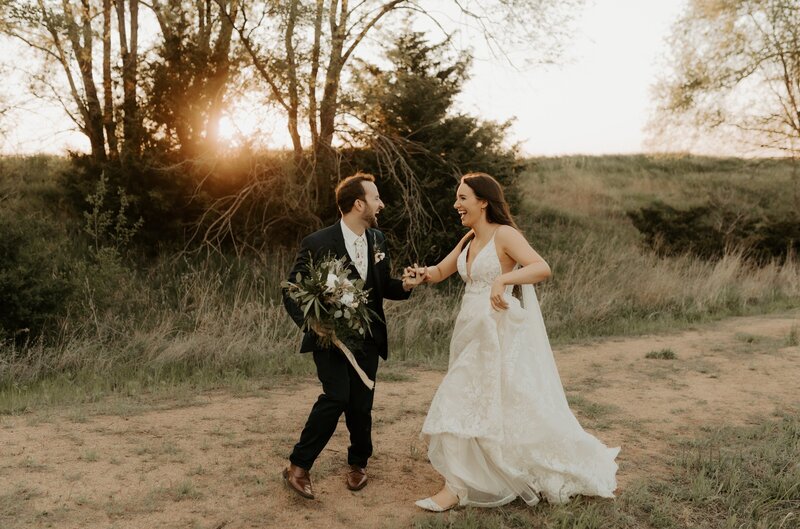bride and groom holding hands dancing and laughing