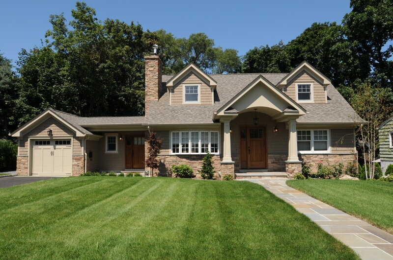 Renovated Craftsman-style home in Huntington featuring stone accents, wood doors, and a landscaped front yard.