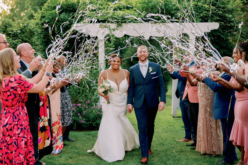 Newlyweds walking through their guests as confetti is thrown on them 