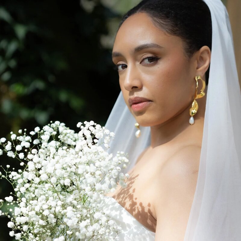 Bride with natural skin-focused makeup and high bun with veil, photographed in soft natural light